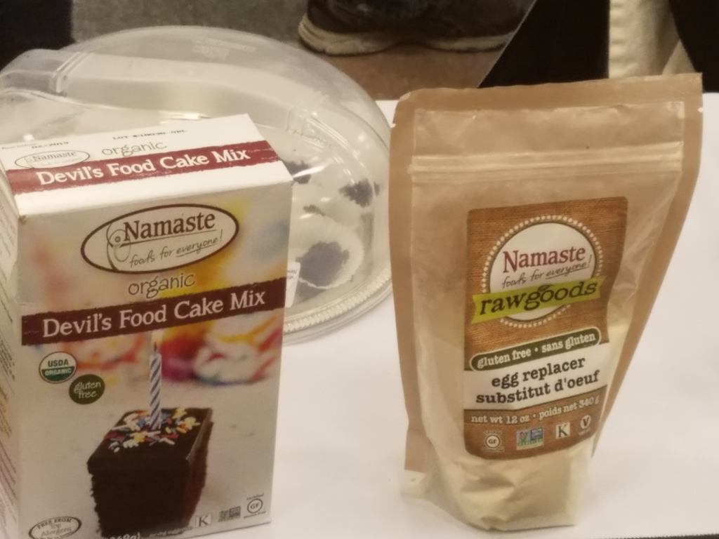 Living well in the 21st century. Limassol, Cyprus. Two containers with a product name - Namaste - foods for everyone. Organic Devil's food cake mix.  The other product says, "raw goods - gluten free - sans gluten - egg replacer - substitut d'oeuf. 