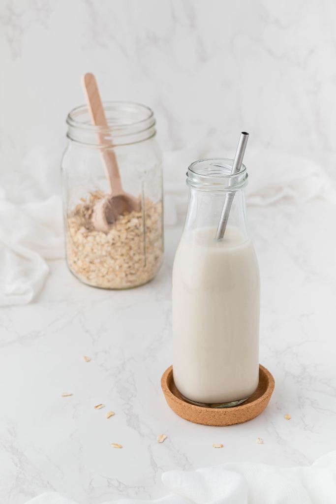 Living well in the 21st century - a picture of almond milk in a container. Next to the container, there is a jar of oats. 